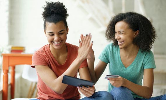 Two women celebrating after a successful online purchase.