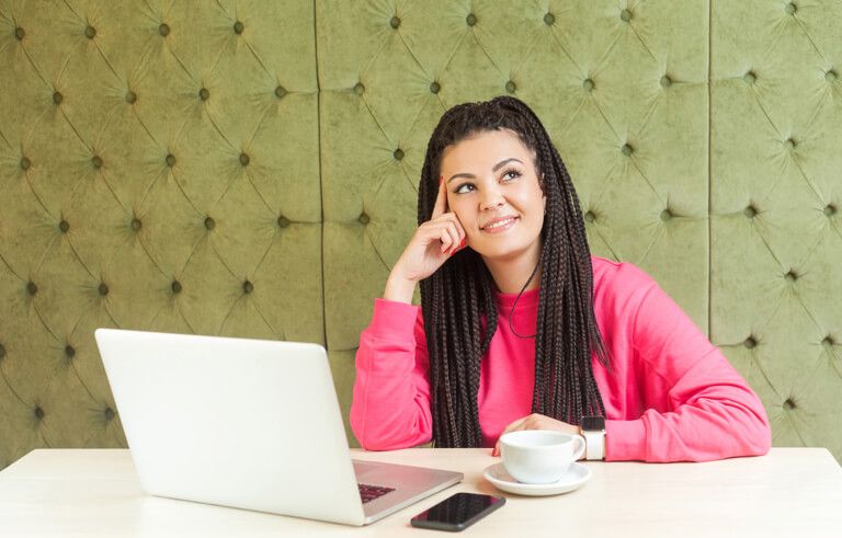 A woman thinking in front of her laptop