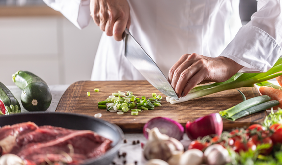 Close-up photo of chef cutting green onions