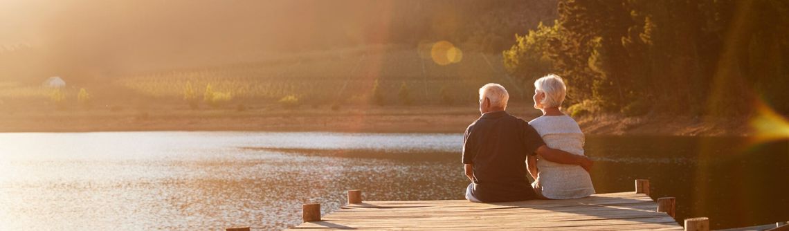 Back view of an elderly couple sitting on a dock