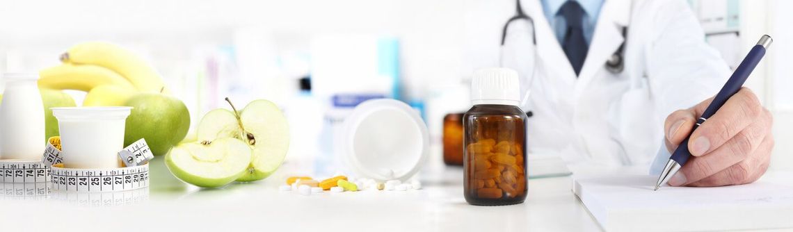 Un médecin écrit une note à côté de fruits et de médicaments sur une table