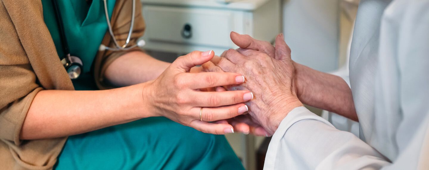 Close up photo of a doctor's hands holding her patient's hands