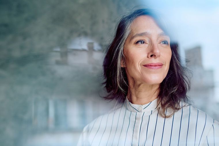 Femme souriante qui regarde à travers une fenêtre.