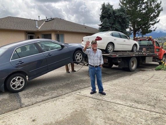 A man in front of a two truck with two cars