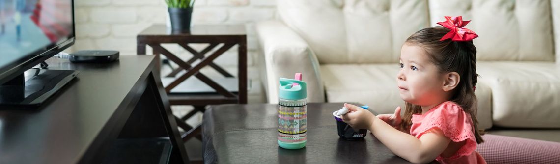 Child enjoying a snack while watching television
