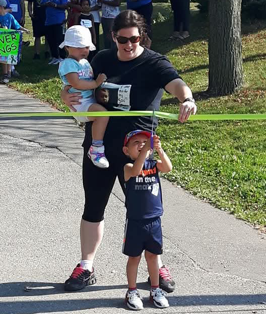 Emmett cut a ribbon while his mother is holding it.