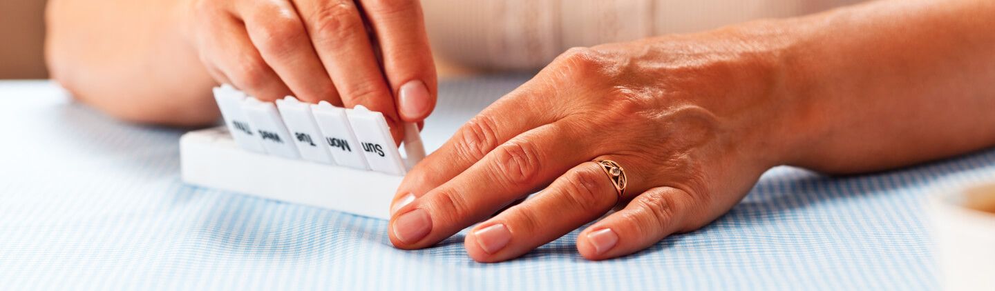 A person's hands managing his medications