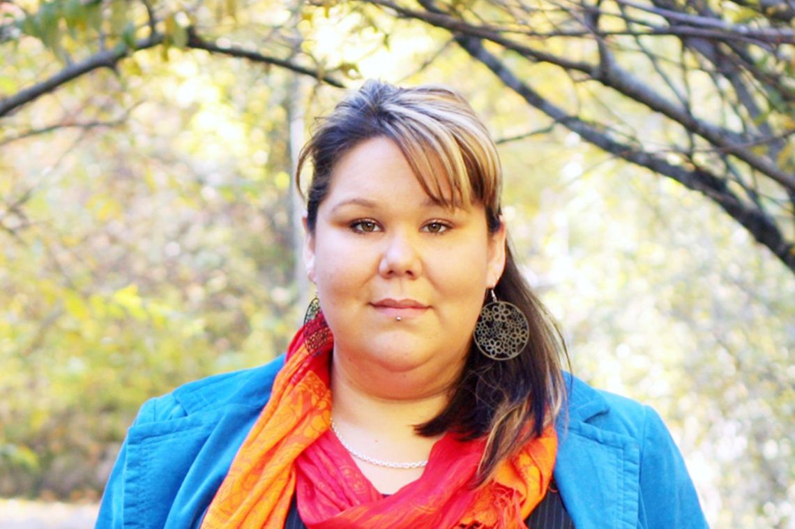 A photograph of a woman standing in an autumn setting.