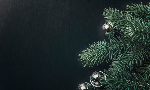 Sapin de Noël orné de décorations argentées sur fond sombre.