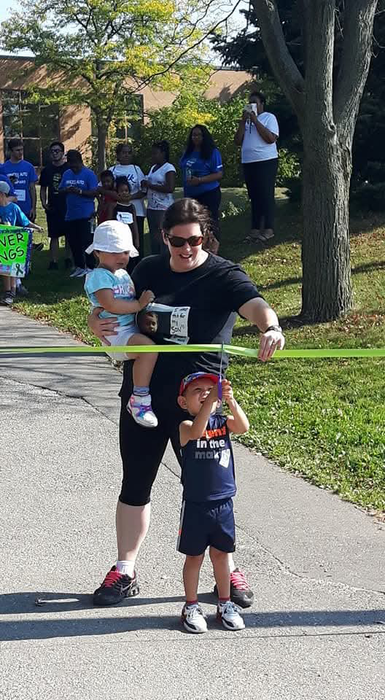 Emmett cut a ribbon while his mother is holding it.