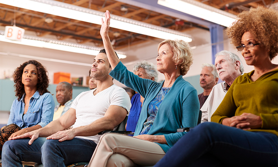 A group of attendees with a woman raising her hand.